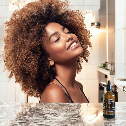 Femme avec chevelure afro qui utilise l'huile fenugrec bio pour ses cheveux